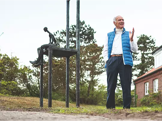 Mike Iwand vor der Skulptur "Mut zum Wagnis" vor dem Hauptgebäude des Inselinternats