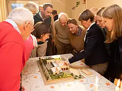 Die Lietzer Paten betrachten mit Erbauerin Marina Meyer das Modell des neuen Handwerksgebäudes.